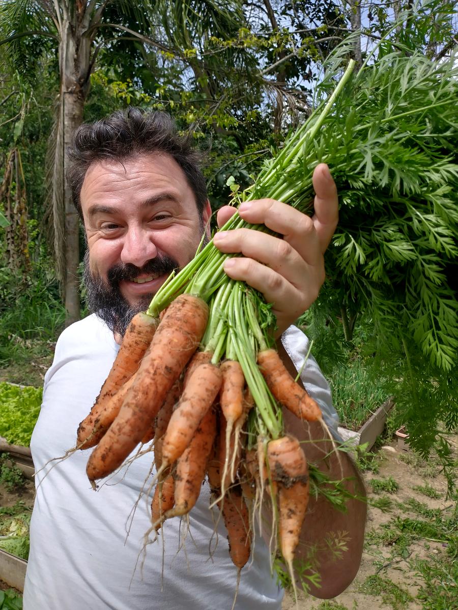 Jones Calisto segurando um maço de cenouras colhidas na horta
